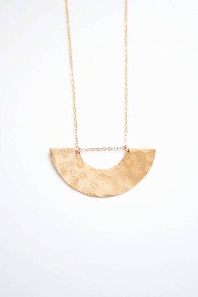 Gold necklace with a half-circle pendant on a white background