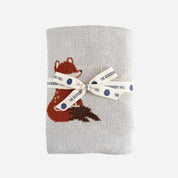 Gray knitted blanket with a fox design and a ribbon label on a white background