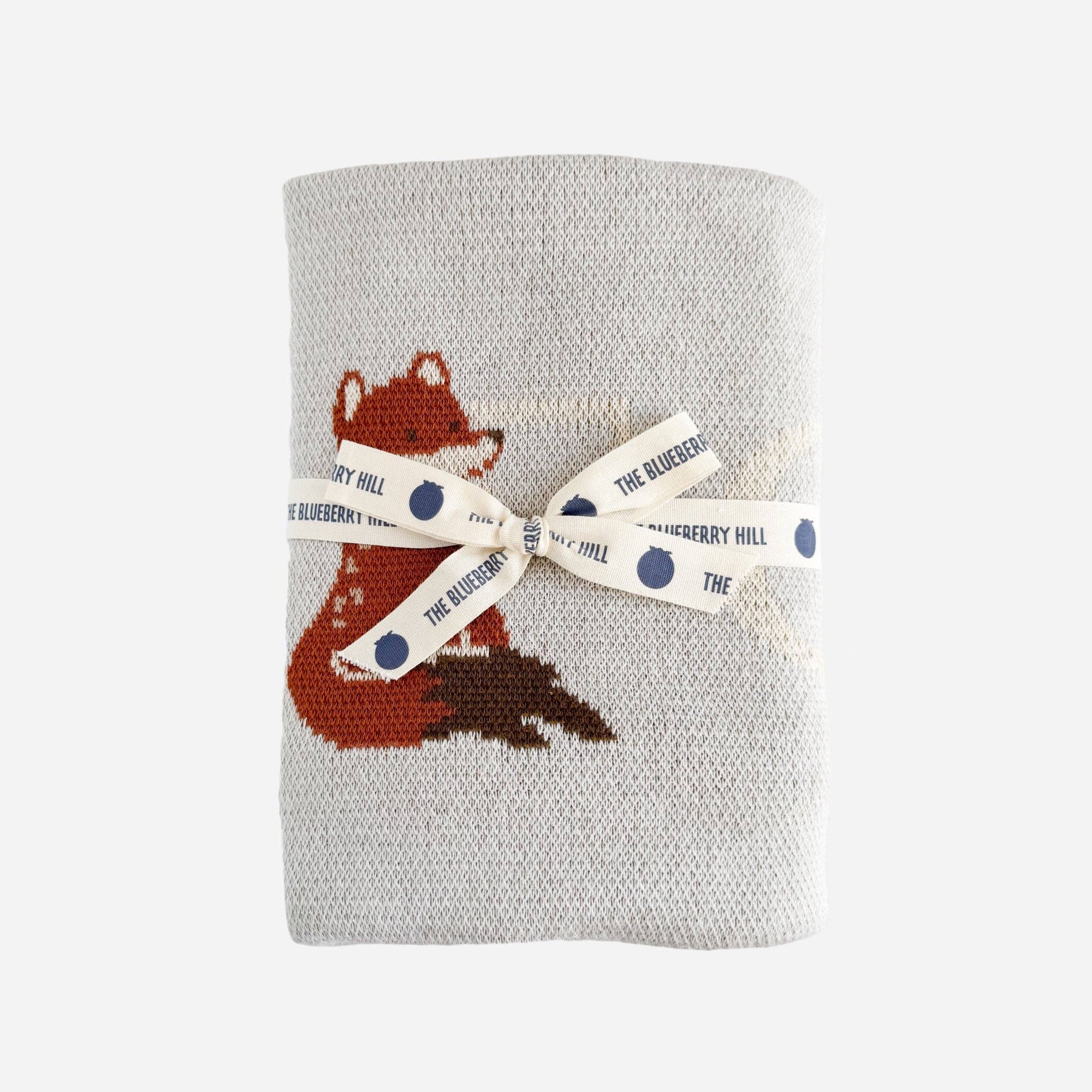 Gray knitted blanket with a fox design and a ribbon label on a white background